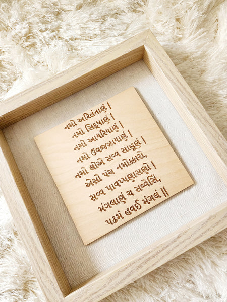 A glass enclosed shadow box is home to wood engraved Namokar or Navkar Mantra.  This mantra is engraved on birch wood and comes in a 9x9 inch shadow box