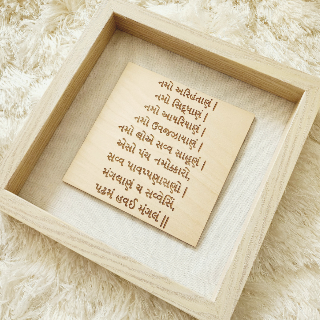 A glass enclosed shadow box is home to wood engraved Namokar or Navkar Mantra.  This mantra is engraved on birch wood and comes in a 9x9 inch shadow box