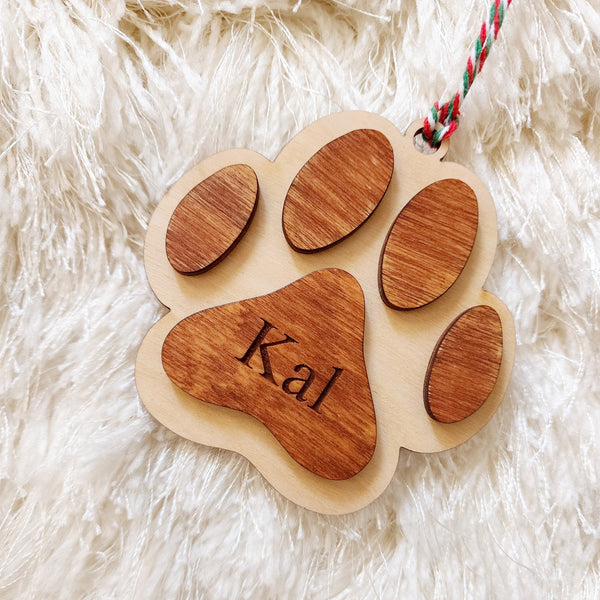 Christmas ornament made with wood in the style of a paw. The ornament is 3D design - 2 layers make up the design with the name engraved in the middle. 